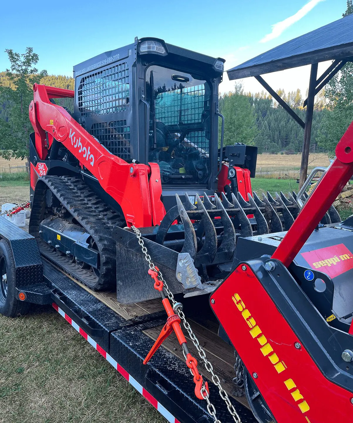Red skid steer loader on a trailer.